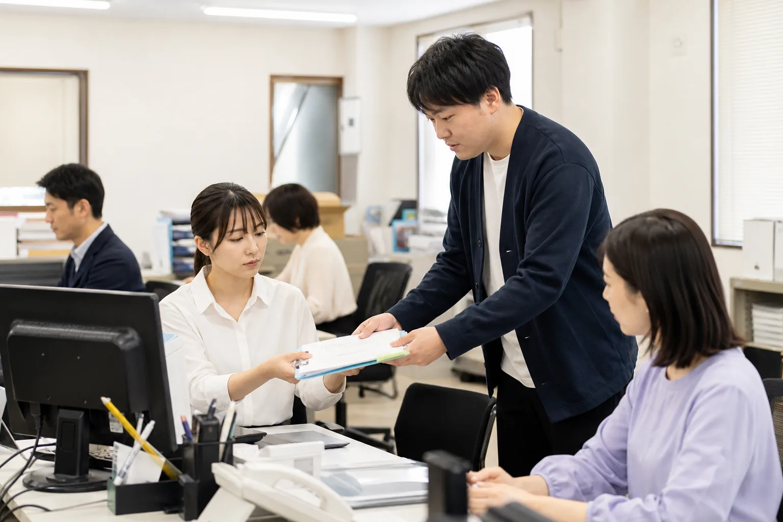 ノートパソコンで電子請求書を確認し、書類を分類する経理担当者
